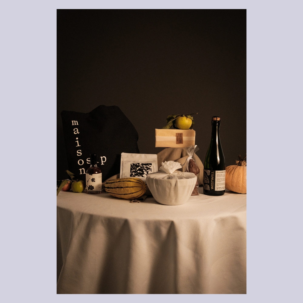 The Osip Christmas Hamper photographed in a dimly lit environment as it lays on top of a white table cloth-covered table.