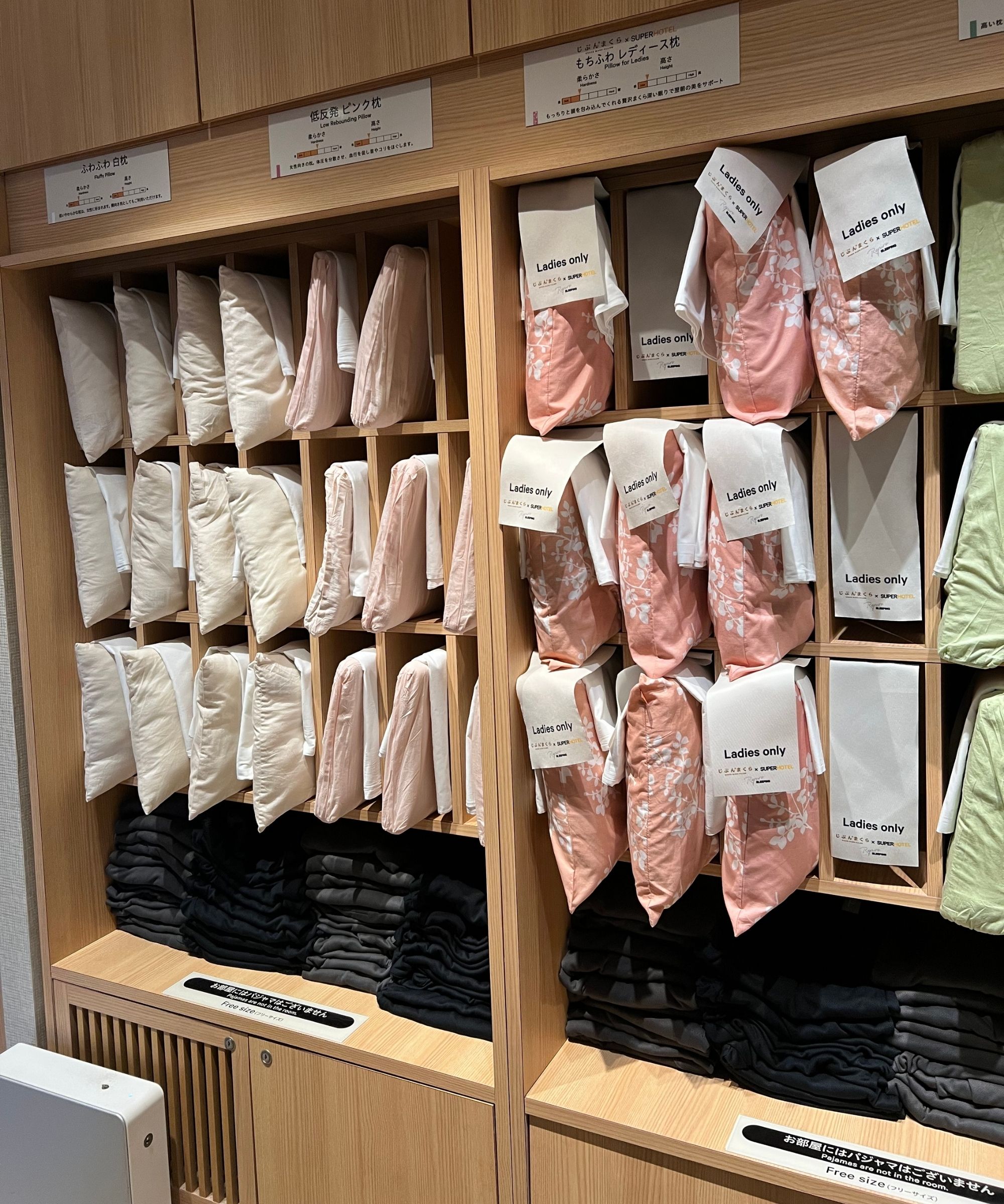 A wooden shelving unit filled with different pillows in different colored pillowcases.