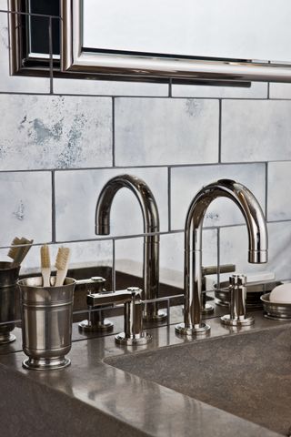 bathroom faucets in front of mirrored tiles