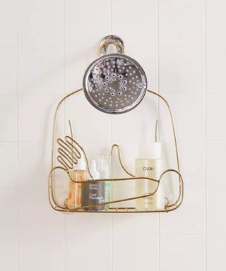 A brass colored shower shelf depicting female chest and hands