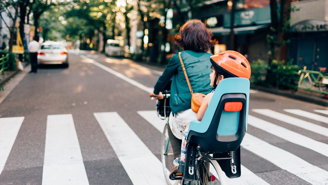 Cyclist rides with child on the back of the bike