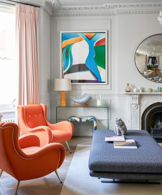 a stylish living room with art and orange accent chairs