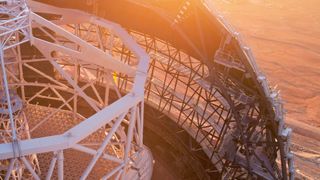 a long, steep stretch of white metal stairs lines the edge of a half-finished dome structure