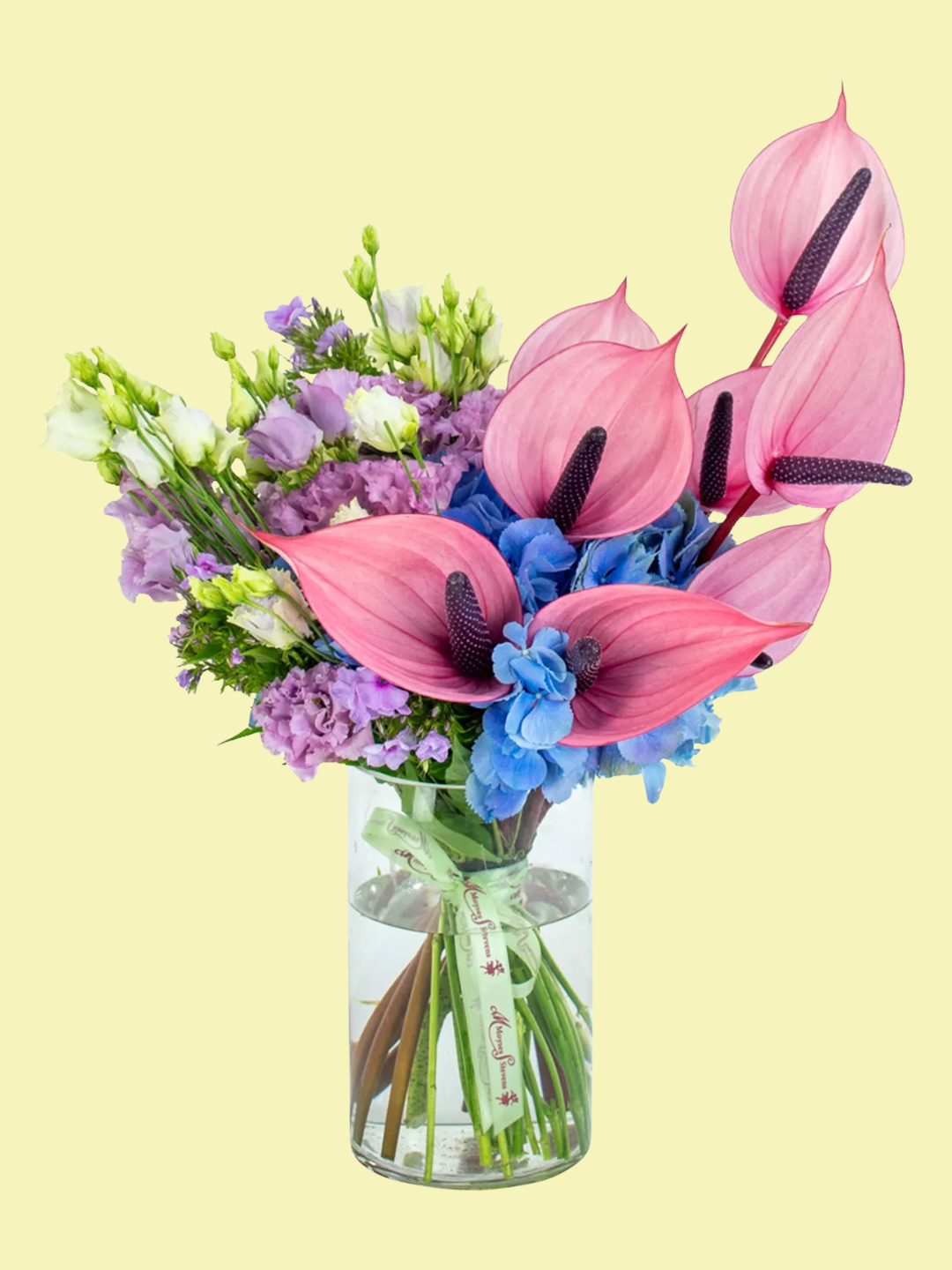 A floral arrangement with pink anthuriums, purple, and blue flowers