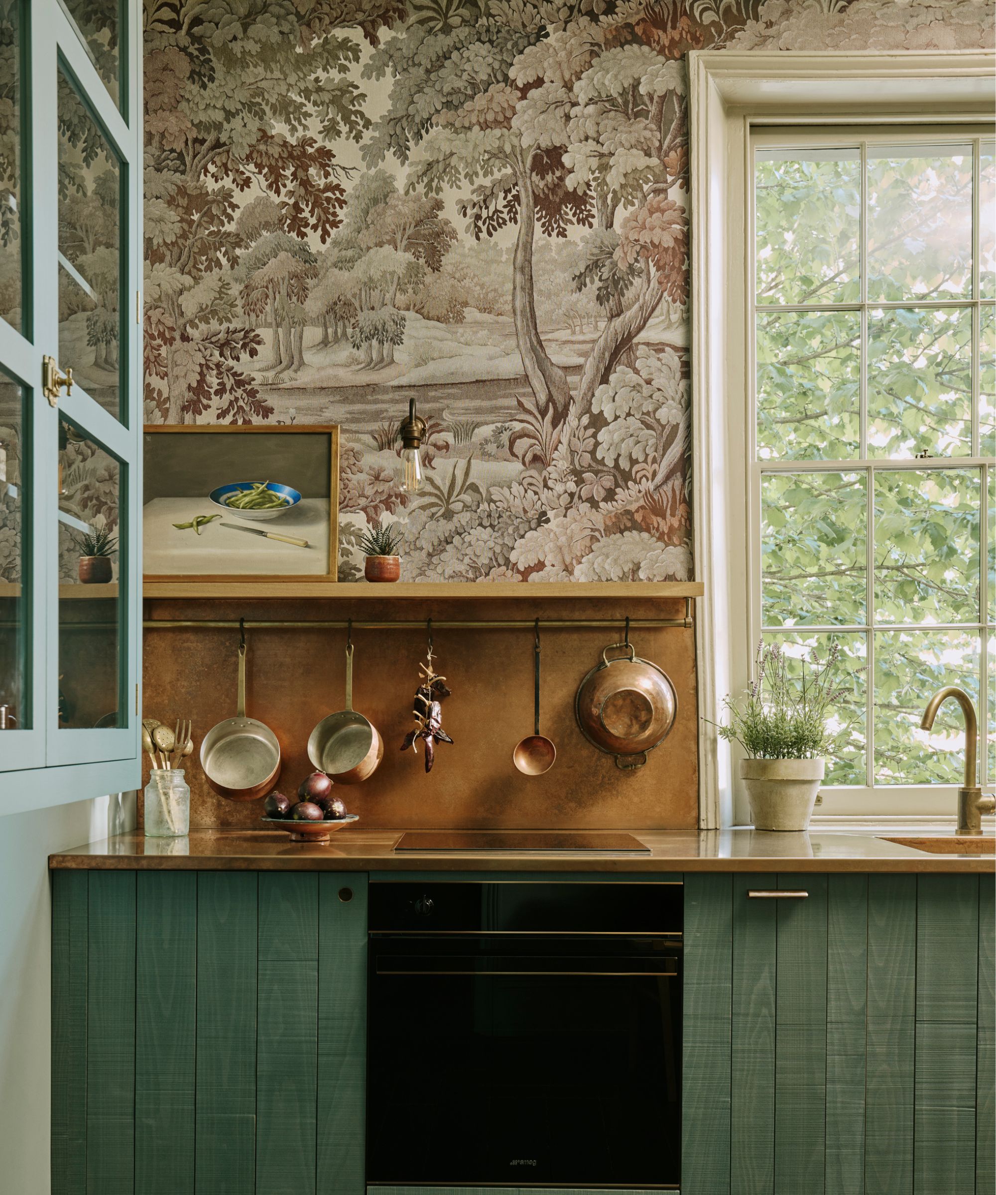 kitchen with green cabinets and brown forest wallpaper on upper wall beside window