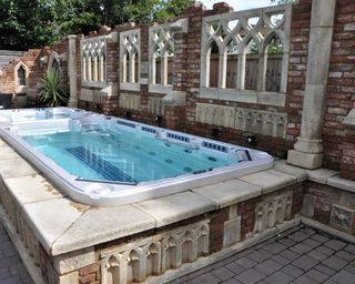 pool surrounded by decorative garden folly wall by redwood stone