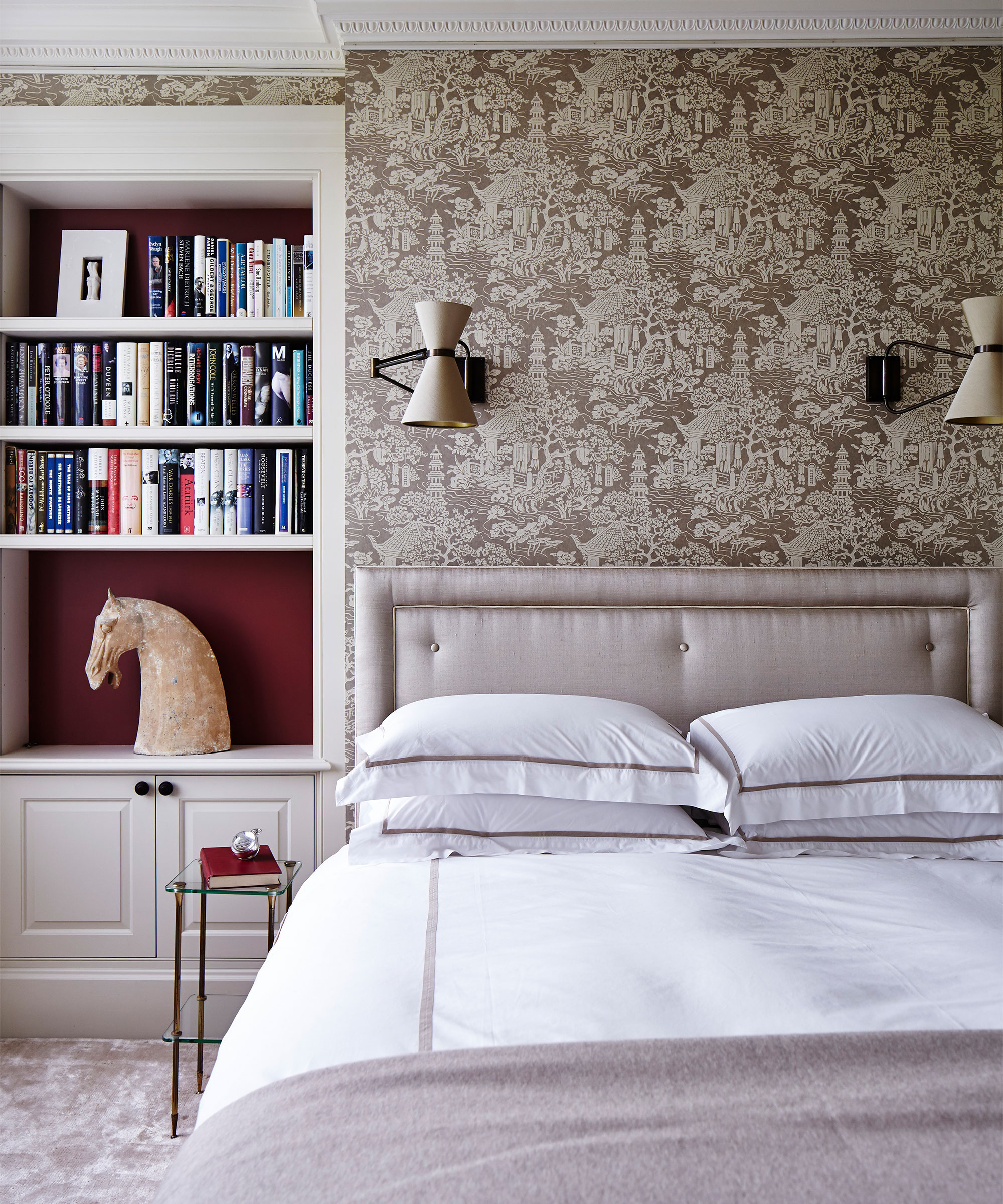 A bedroom with patterned wallpaper and a pink silk bed.