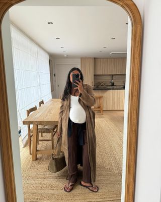 Monikh Dale in a brown suede jacket, white tank top, and brown pants.