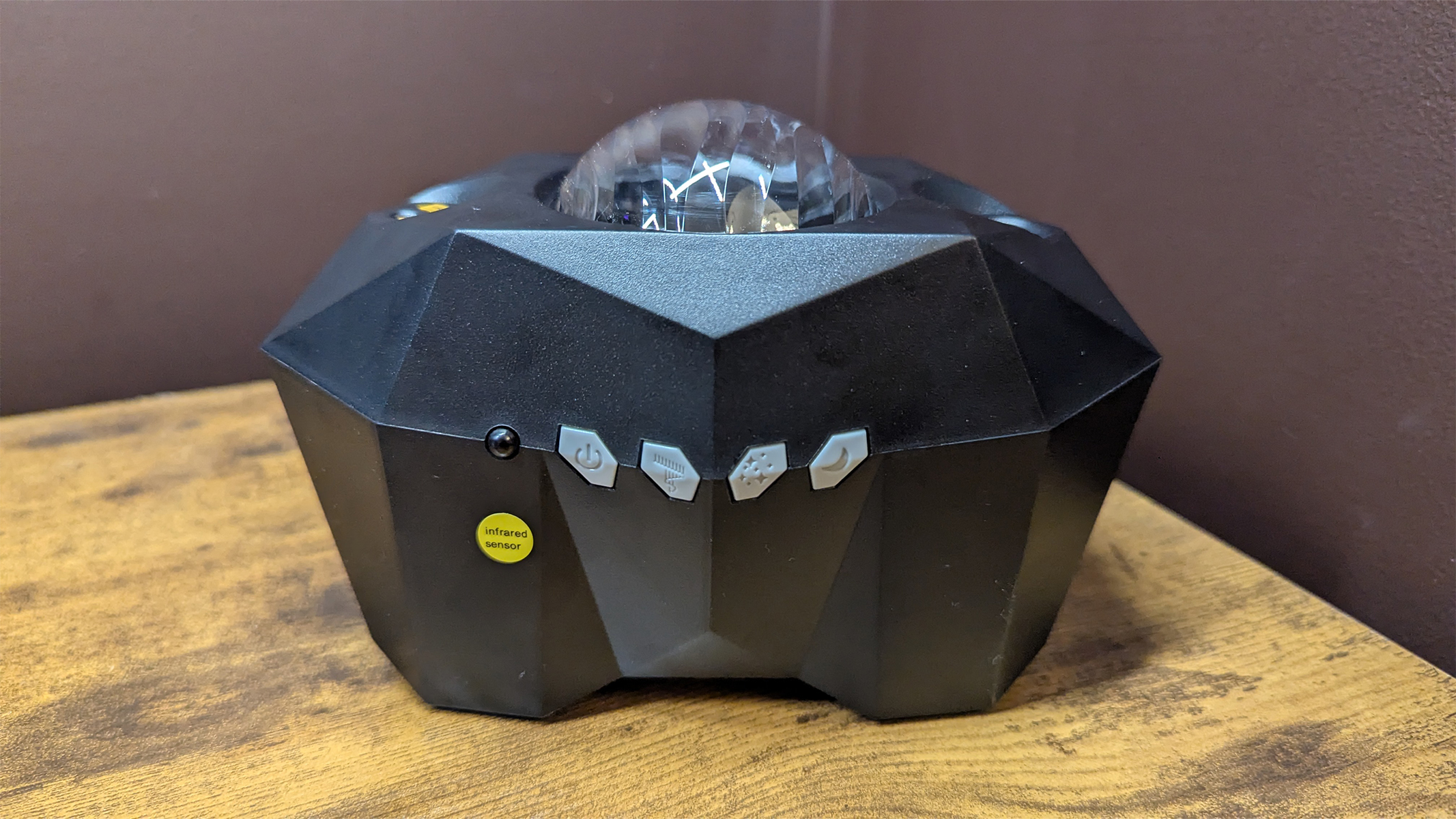 Cadrim Star Projector on a table with a brown wall behind it