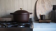 a oven gap filler on a stainless steel stove next to a brown pot with a marble oval board