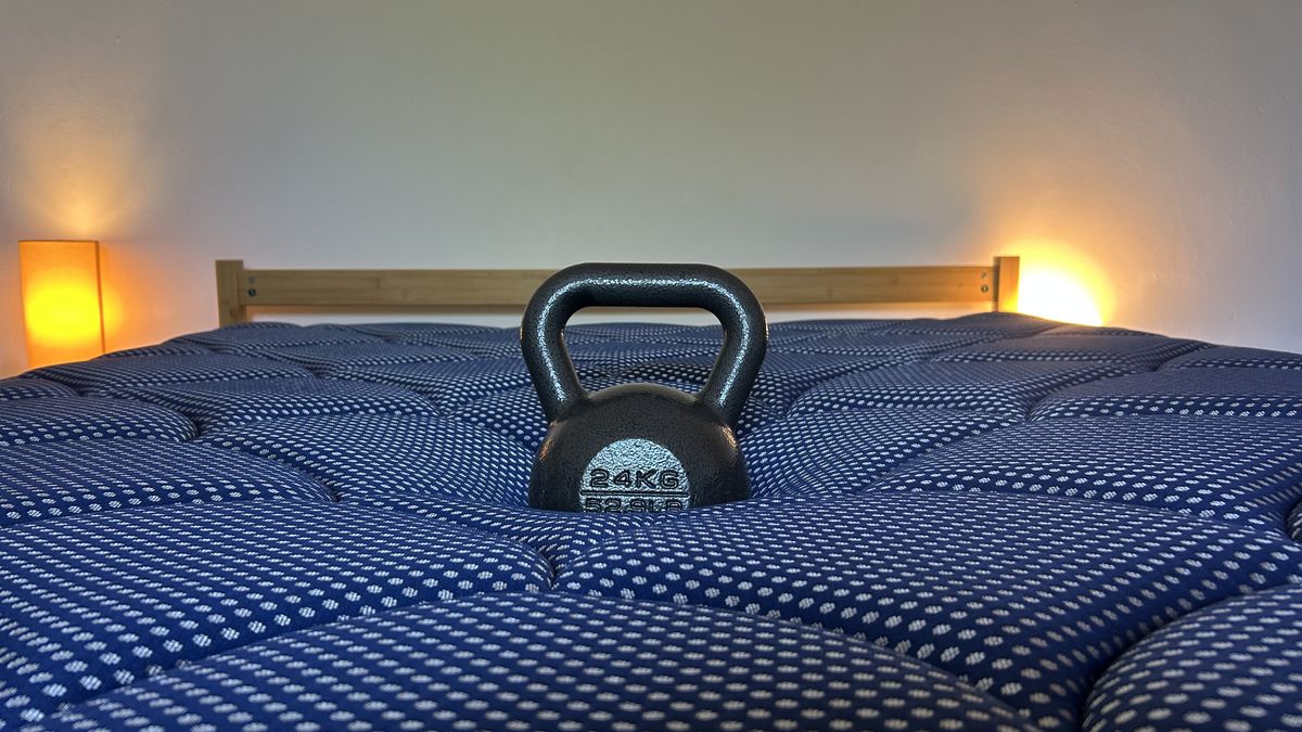 Assessing the comfort and support of the DreamCloud Luxe Memory Foam mattress by measuring how far a weight sinks in the middle of the bed.