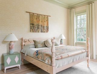 bedroom with yellow patterned wallpaper, green woodwork, green bedside chest, wooden bed and patterned throw