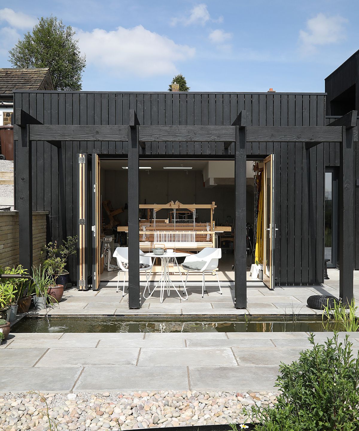 A single storey self build studio workspace with a water feature and timber pergola