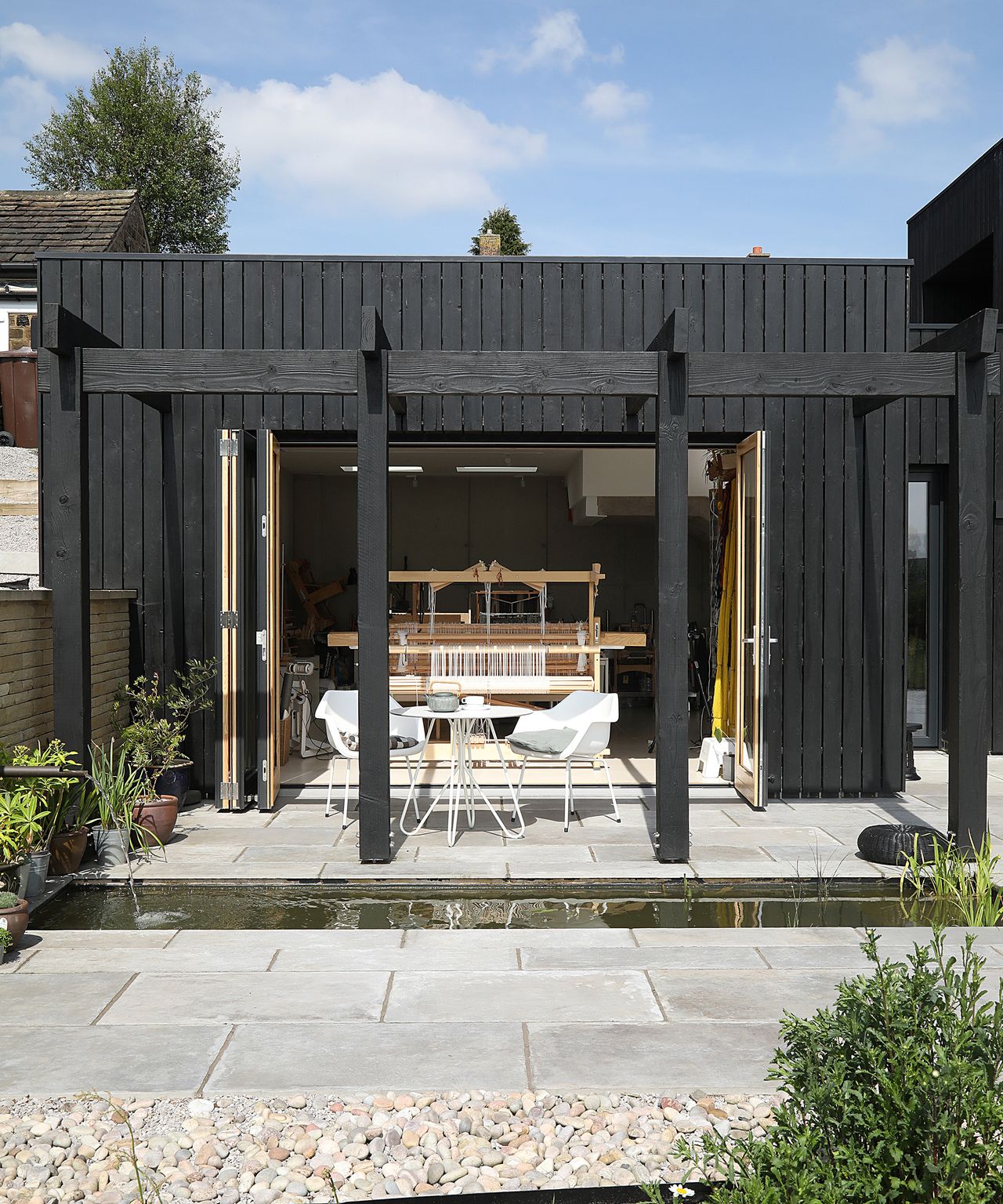 A single storey self build studio workspace with a water feature and timber pergola
