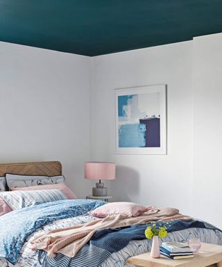 Teenage bedroom with white walls and teal ceiling, bed with wooden headboard and pink, blue and white bedding.