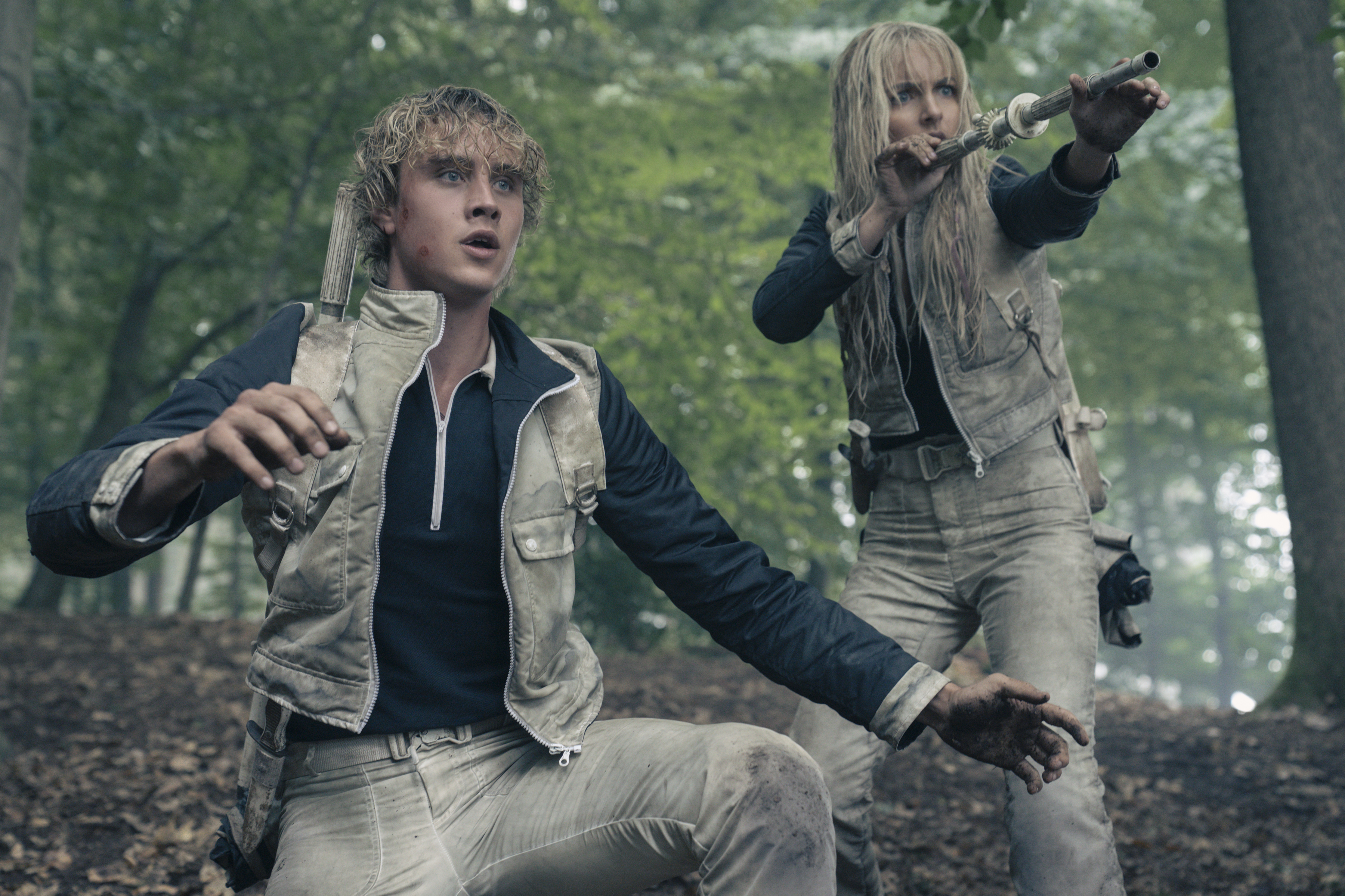 joseph zada as haymitch and mckenna grace as maysilee donner shooting in the woods in dirty white clothing in a still from the hunger games sunrise on the reaping