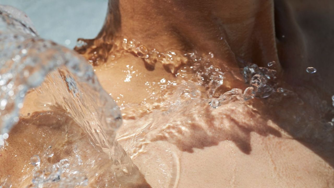 A woman with water splashing on her collarbone