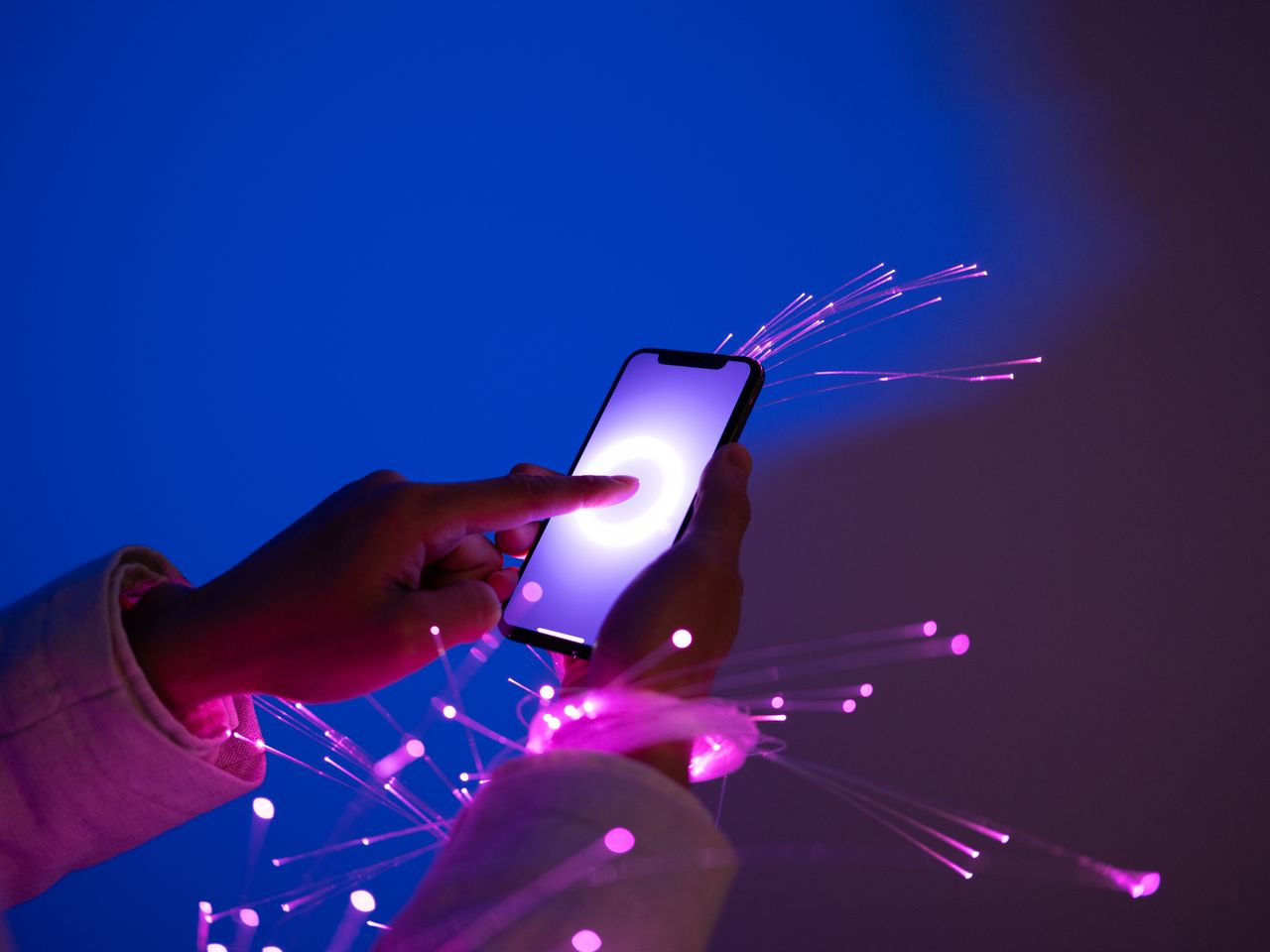 Close-up of holding smartphone, arms wrapped with fiber optics