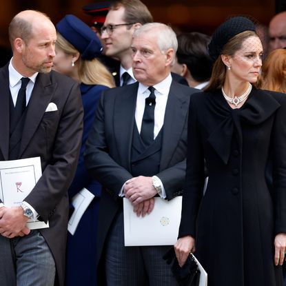 Prince Andrew, Prince William and Princess Kate standing in a row wearing black at a funeral