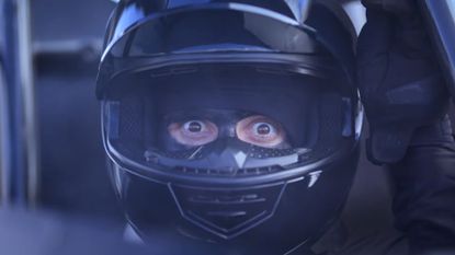A racecar driver lifts his visor and stares, bug-eyed, at the viewer in an ad for Sonic Racing: CrossWorlds