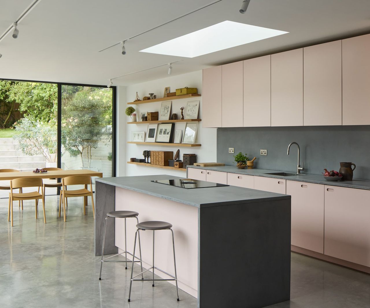 A kitchen with pink cabinets and a grey kitchen island and rooflights