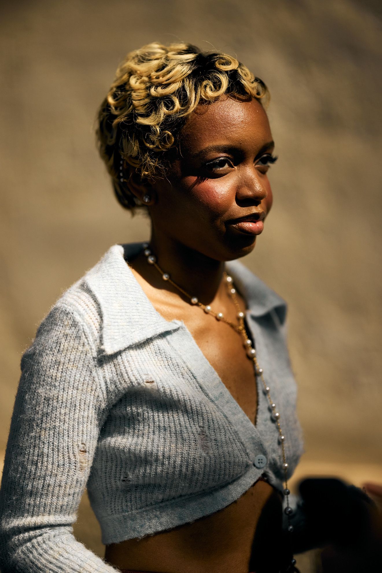 a black woman with a blonde pixie cut in a gray sweater