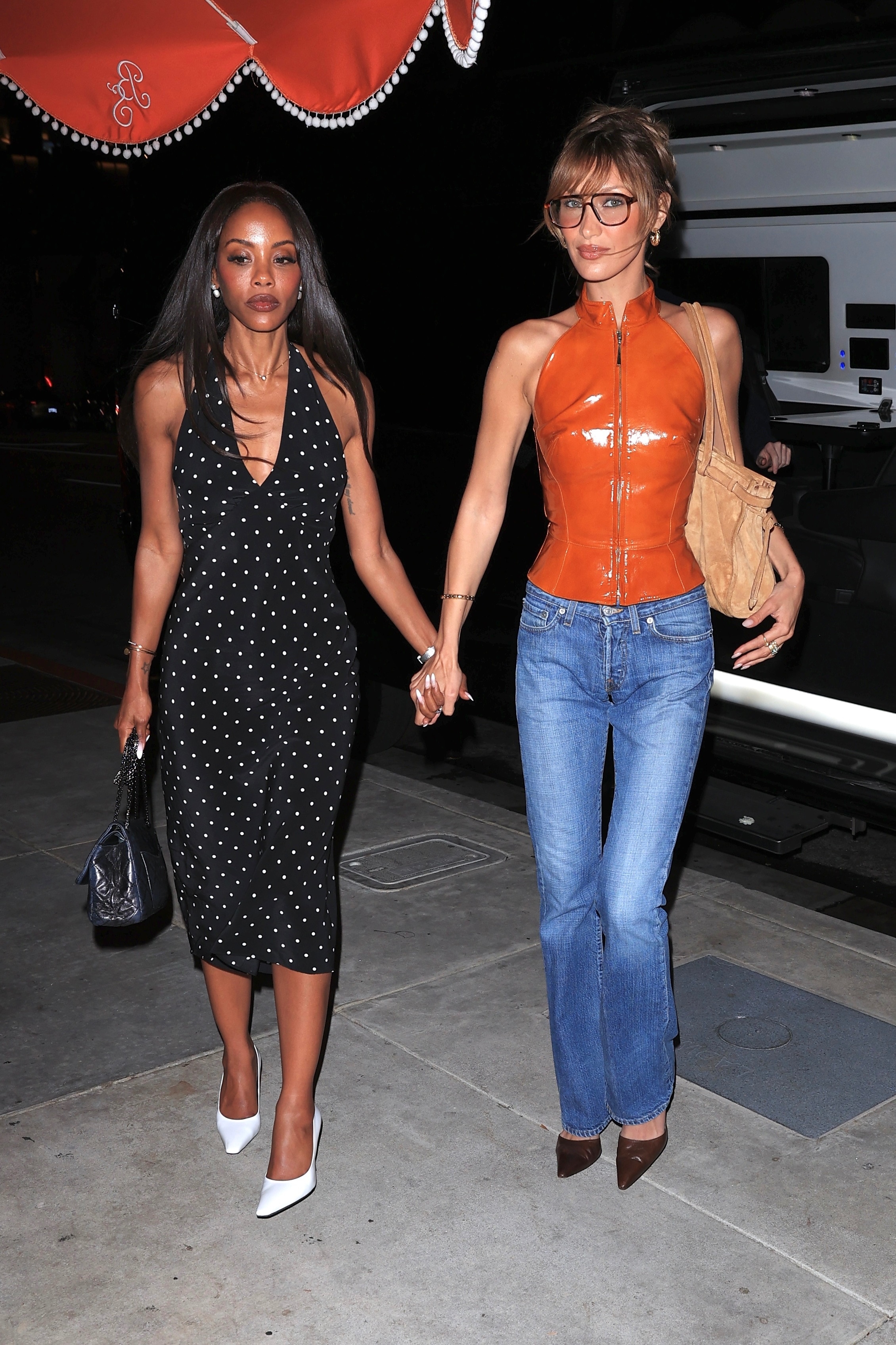 Bella Hadid wears bootcut jeans, brown pointed-toe mules, an orange PVC zip top, and carries a Prada Bonnie suede bag ShotbyNYP / BACKGRID