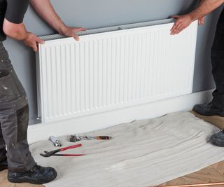 white radiator being installed on blue wall