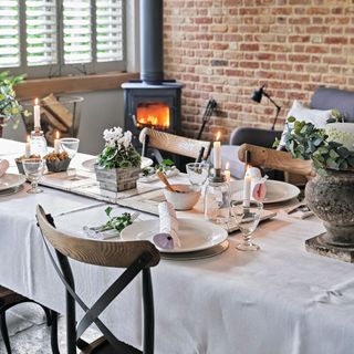 dining table in front of log burner and exposed brick wall