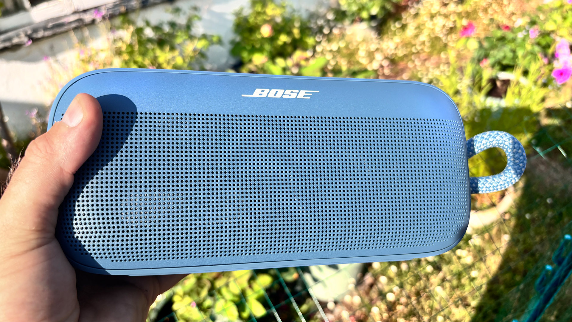 Bose SoundLink Plus wireless speaker held in hand in garden