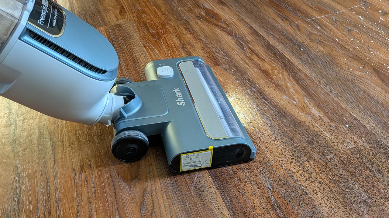 Tester using the Shark Freestyle Max cordless upright vacuum to clear dry tea from a hard floor