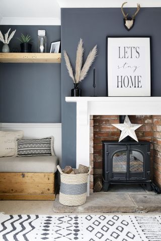 Blue painted living room with brick fireplace, bench seating and monochrome rug