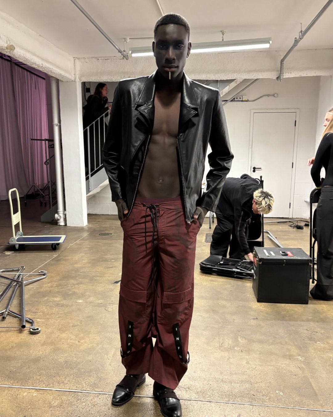 an image of a model, modou at London Fashion Week in a leather jacket and red trousers