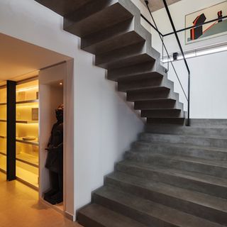 The main entrance corridor features built-in display units, while a bold, concrete staircase links the two floors