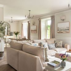 Open plan living space in cottage, dining room and living room, neutral decorated with high windows