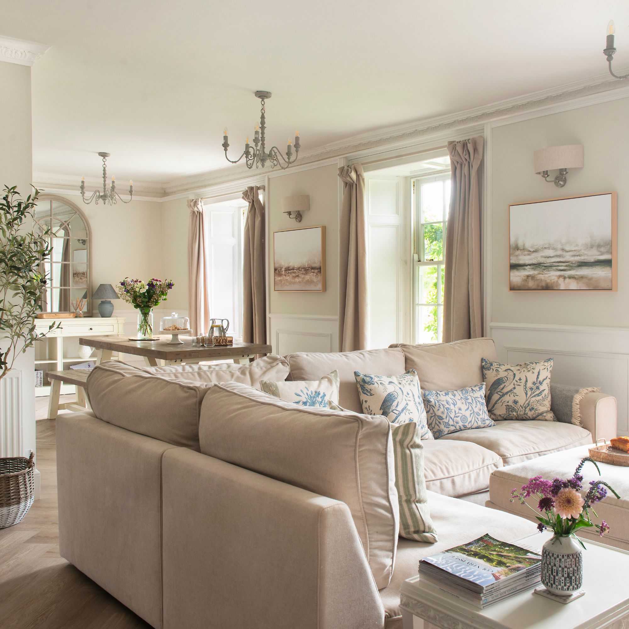 Open plan living space in cottage, dining room and living room, neutral decorated with high windows