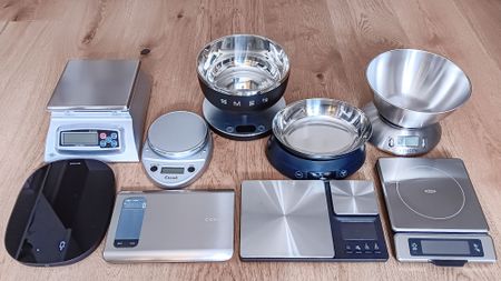 Collection of kitchen scales ready for testing on a wooden table in a kitchen