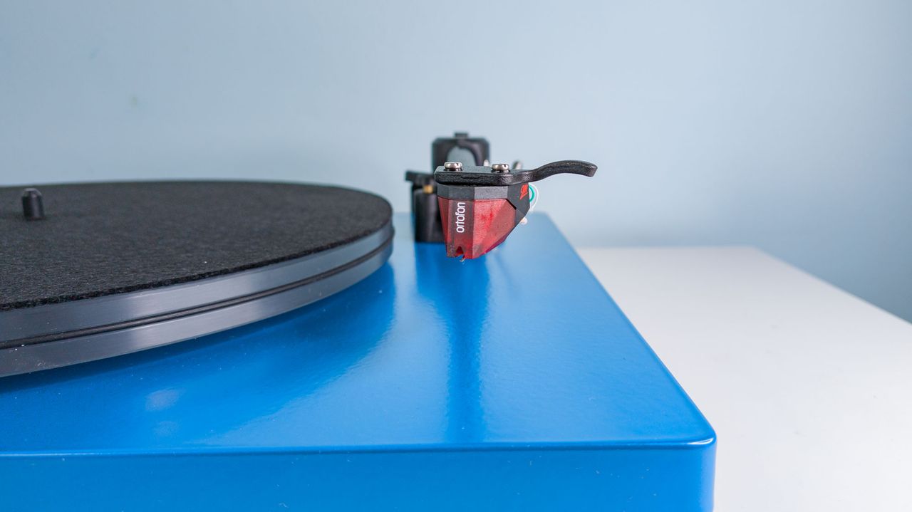 A closeup of the Ortofon 2M red cartridge at the end of the tonearm of a blue U-Turn Audio Orbit Special turntable