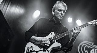 Duane Denison of The Jesus Lizard plays a chord on his Travis Bean electric guitar, in this black-and-white live shot from the audience's POV.