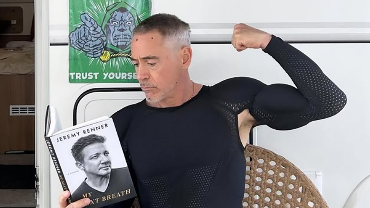 An image of Robert Downey Jr reading Jeremy Renner&#039;s autobiography while sitting in front of his Avengers: Doomsday trailer