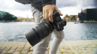 Nikon Z 135mm f/1.8 S Plena lens held in a hand of a photographeras they walk