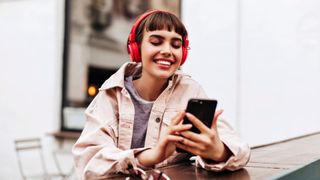 A person looks at their phone while wearing headphones