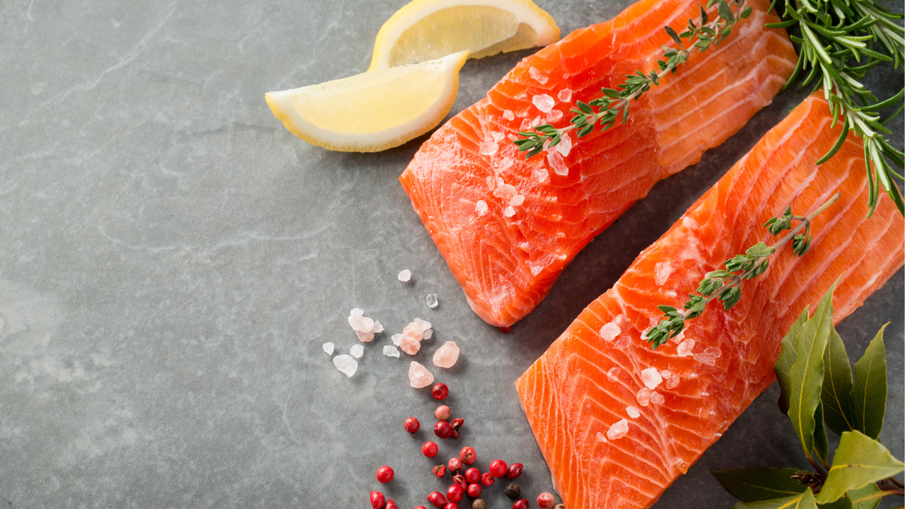 Trout fillets on a slate slab, with herbs, spices and lemon wedges