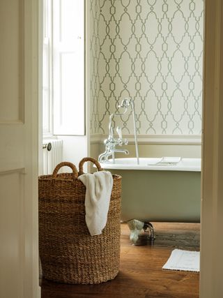 A large wicker laundry basket with a removeable lid in the doorway of a country bathroom