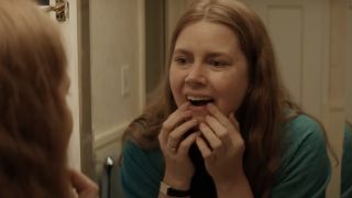 Amy Adams examining her teeth in a mirror in Nightbitch