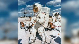 Astronauts John W. Young, left, Apollo 16 commander, and Charles M. Duke Jr., lunar module pilot, simulate a lunar traverse.