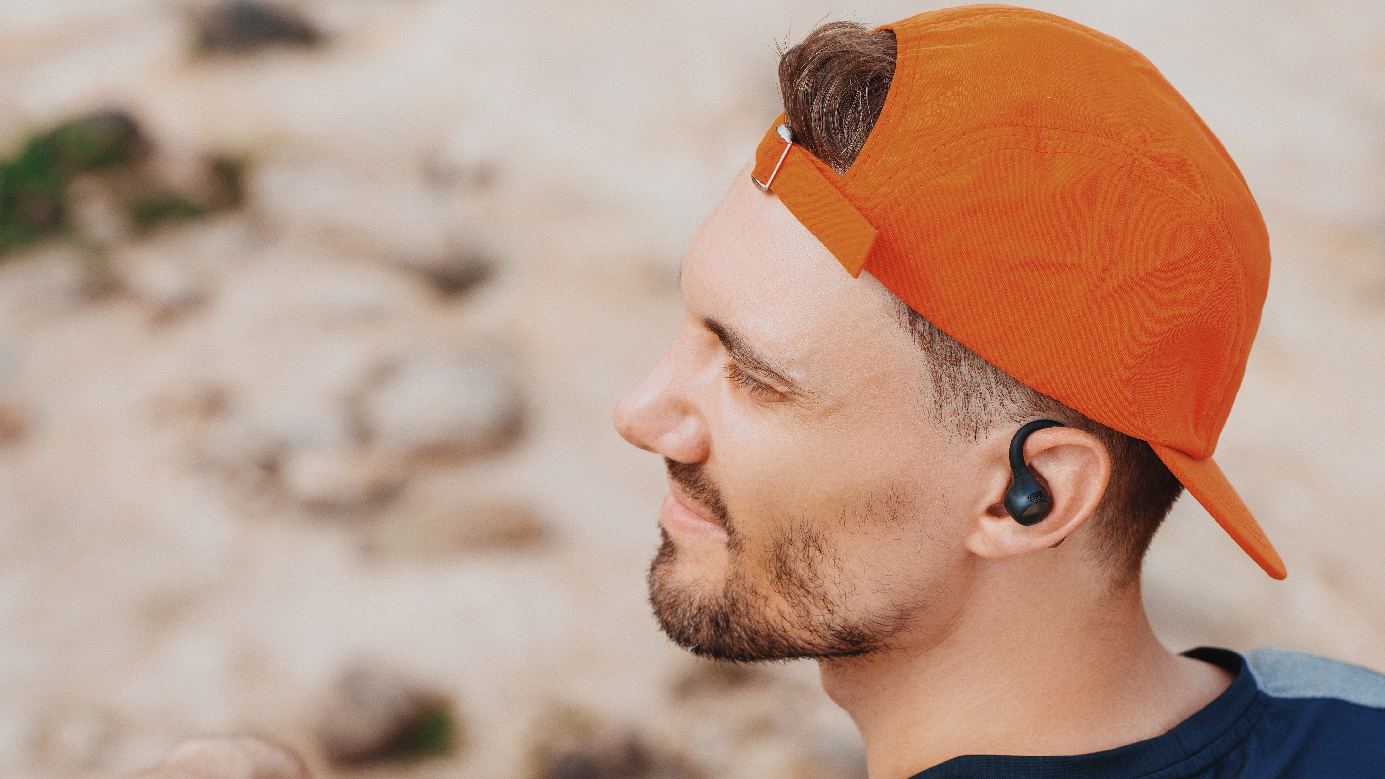 Man with a cap wearing OpenRock headphones