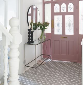 Patterned flooring in a hallway with a pink door