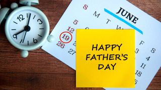 An alarm clock and calendar with a Father's Day Post-It note attached