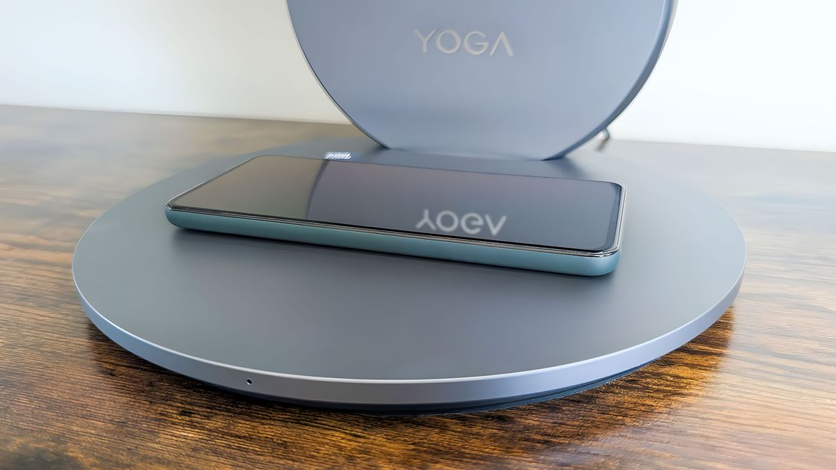 A phone resting on the Lenovo Yoga AIO 27"'s wireless charging base.